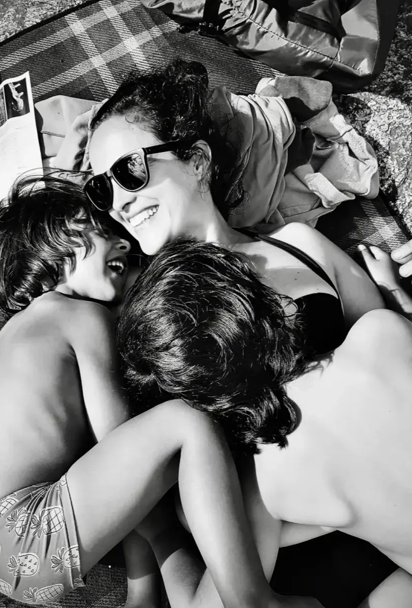 Noemí laughing with her two children in a sunny outdoor moment